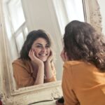 A woman smiling at her reflection in the mirror.