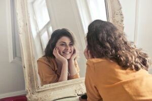 A woman smiling at her reflection in the mirror.