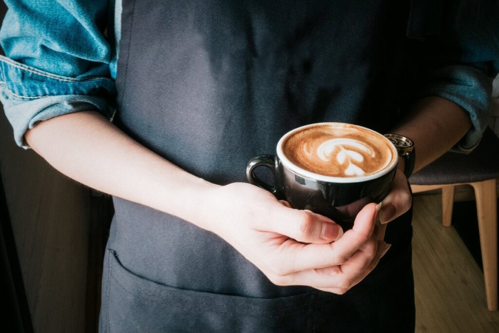 Barista holding a cup of coffee.
