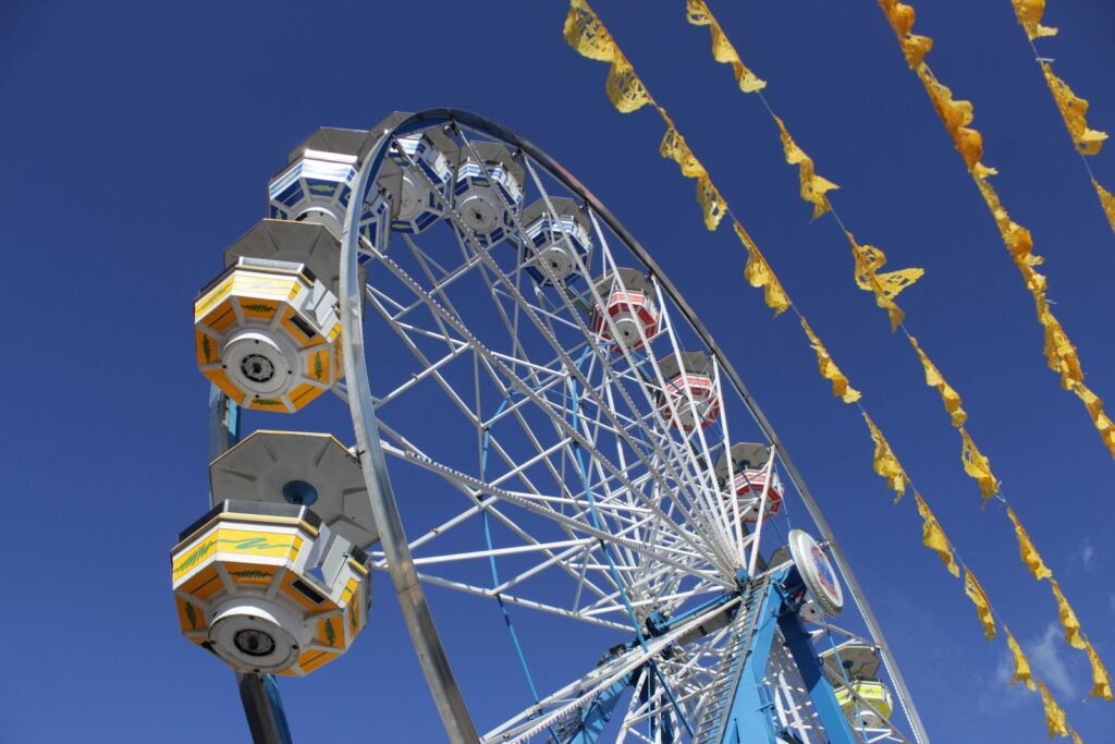 Image of a ferris wheel against a bright blue sky.