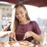 A woman smiling while eating a pizza.